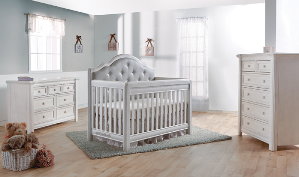 The <b>Cristallo Forever Crib</b> in Vintage White and with a <b>gray vinyl upholstered panel</b> headboard. <br>Like the playful nature of light that bounces off a crystal and makes rainbows on the wall, the architectural shapes paired with the upholstered cushion of the Cristallo Forever Crib provide a playful combination of refined styling and chic design.  The Cristallo Forever Crib is an enchanting blend of classic lines paired with sweet touches of sophisticated luxury.  The strong, clean design of this crib is highlighted by the layered moldings that frame both the front and the headpiece.  These beautifully rounded layers provide texture and a nod to the elegance of classical architecture.  Set in the headpiece of the crib is a sumptuously tufted panel. Providing a distinct sense of playful beauty, this sweetly textured cushion is designed with both style and use in mind. 
